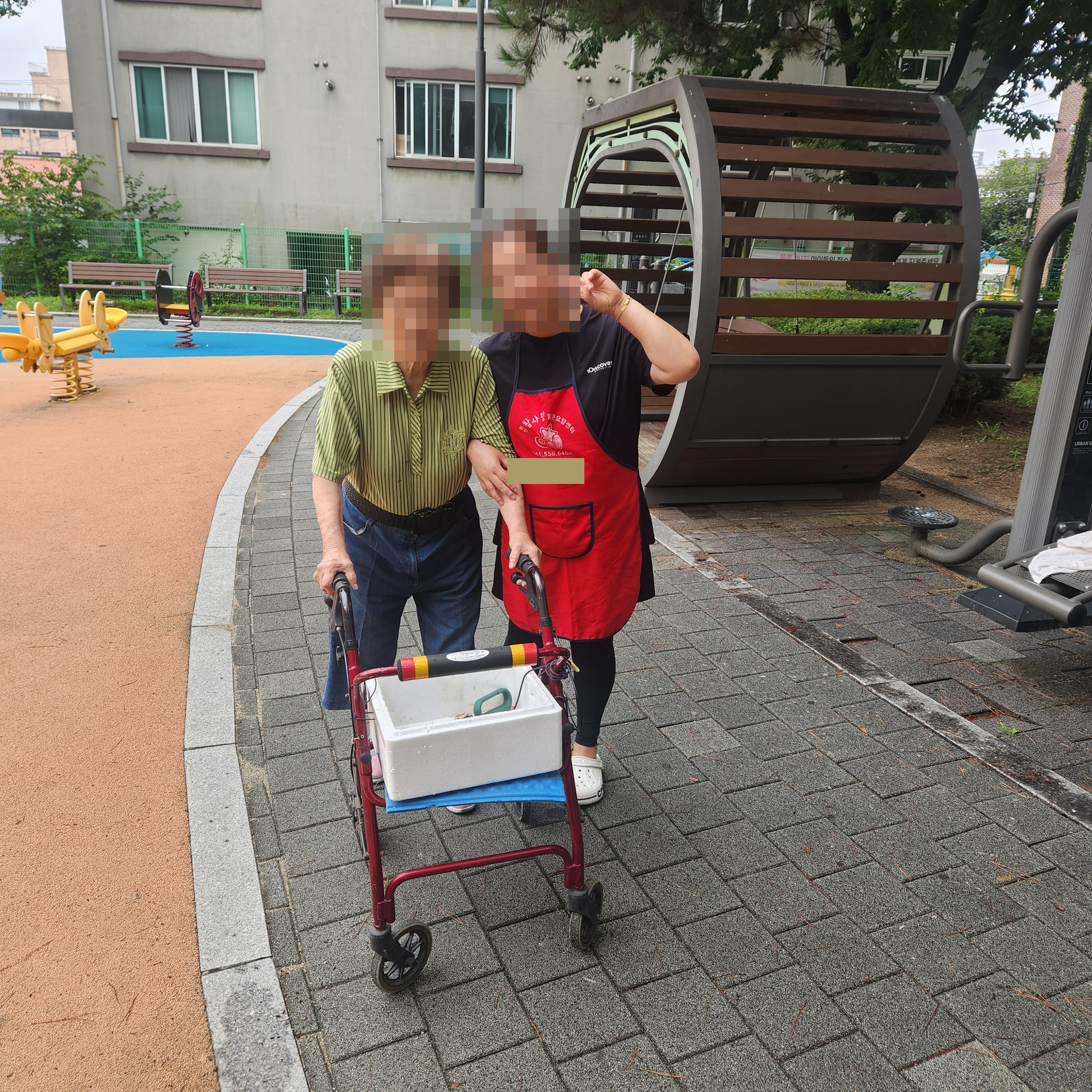 요양보호사와 함께 보행보조 카트를 이용해 야외를 이동하는 어르신